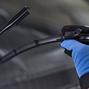 Technician's Hand Holding a Wiper in Front of a Windshield Representing  Wipers  and Washers Maintenance Parts Category